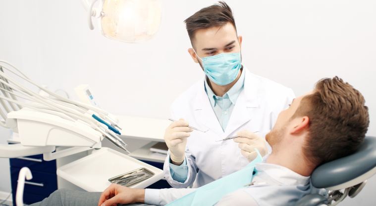 male dentist talking to a patient sitting in dentist chair