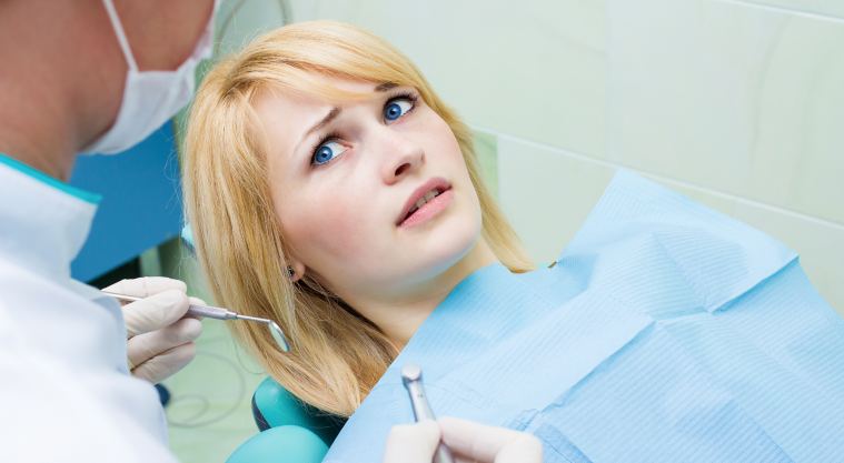 woman sitting in dentist chair scared of dentist